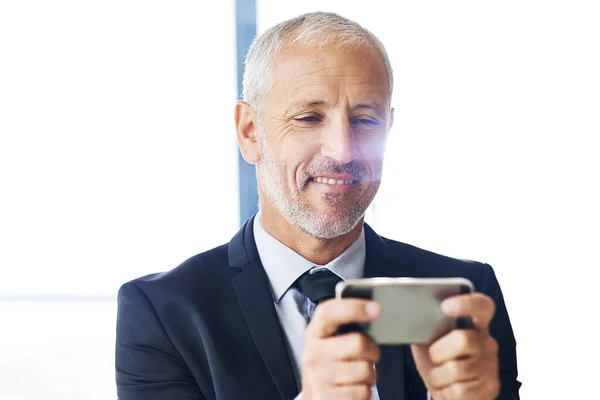 Organizando sus reuniones para el día. Recorte de un hombre de negocios maduro mensajes de texto en un teléfono celular en una oficina. —  Fotos de Stock