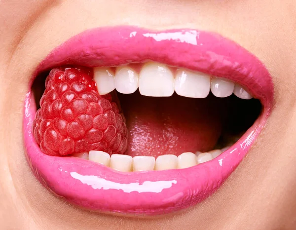 Deliciosas frambuesas. Tiro de una mujer con lápiz labial rosa y morder una frambuesa. — Foto de Stock