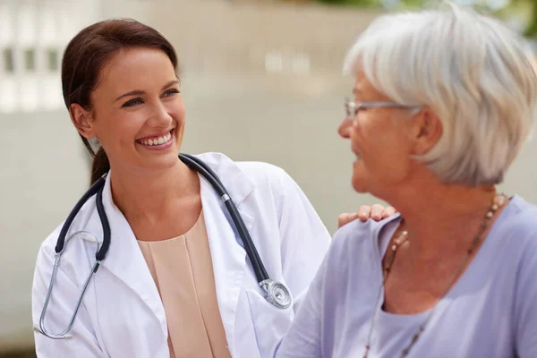 Vriendelijk en zorgzaam professioneel. Schot van een lachende dokter die praat met een oudere patiënt.. — Stockfoto