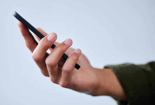 Um dispositivo que me mantém ligado a tudo. Tiro de perto de um homem irreconhecível usando um celular contra um fundo branco. — Fotografia de Stock