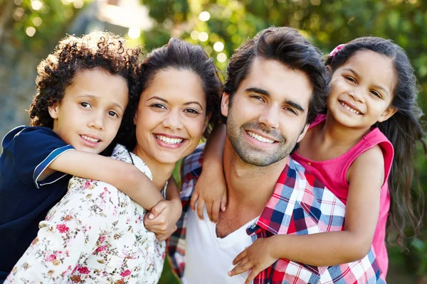 Sie sind so eine süße Familie. Ein junges Paar huckepack mit seinen kleinen Kindern im Park. — Stockfoto