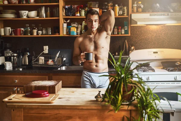 A desfrutar de uma chávena de café na cozinha. Tiro cortado de um belo jovem sem camisa bebendo uma xícara de café na cozinha em casa. — Fotografia de Stock