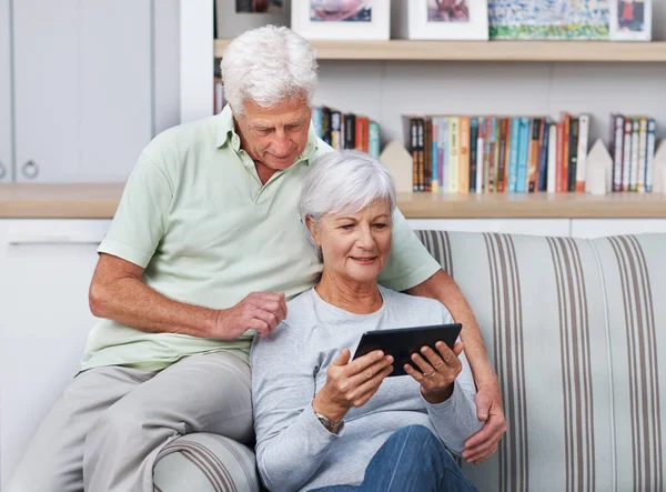 Qué ingenioso artefacto. Una pareja de ancianos relajándose en su casa con una tableta digital. — Foto de Stock