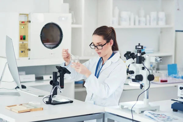 Ela sabe o que está a fazer. Foto colhida de uma jovem cientista focada misturando produtos químicos em sua mesa dentro de um laboratório. — Fotografia de Stock