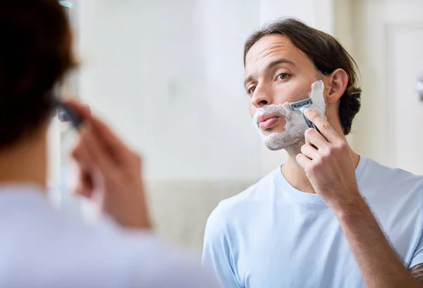 Take your time to prevent accidents. Shot of a young man shaving his face in the morning. — Stock Photo, Image