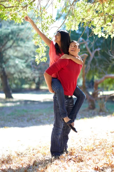Divertirse al aire libre juntos. Fotografía de un joven guapo dando a su novia un paseo a cuestas en el parque. — Foto de Stock