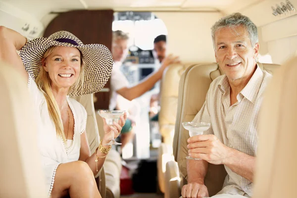 Volando con estilo. Foto de una pareja madura sentada en la parte posterior de un jet privado bebiendo cócteles. —  Fotos de Stock