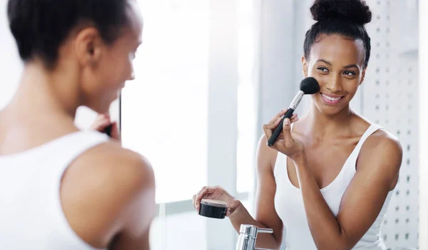 Añadiendo un poco de glamour a su encantadora cara. Foto de una joven atractiva que se aplica maquillaje en su cara en su baño en casa. — Foto de Stock