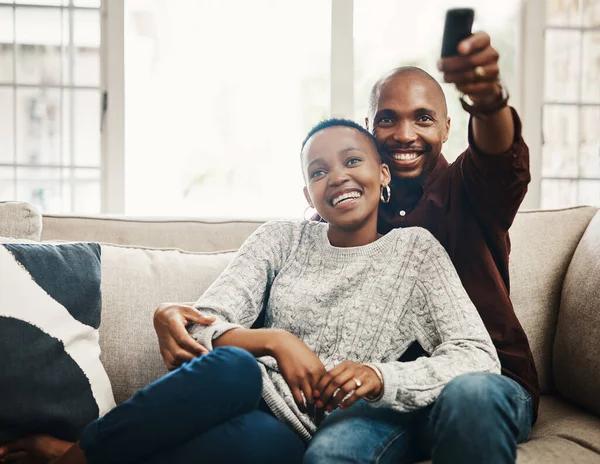 Il est temps de rattraper notre retard sur nos émissions préférées. Tourné d'un jeune homme heureux changer la chaîne de télévision alors que passer du temps avec sa petite amie à la maison. — Photo