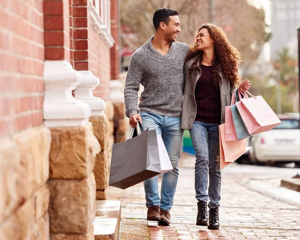 Att få in lite välbehövlig detaljhandelsterapi. Full längd skott av en tillgiven ung par njuter av en shoppingrunda i staden. — Stockfoto