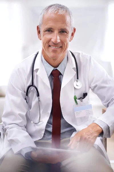 Tratamiento con una sonrisa. Retrato de un médico sentado en su consultorio. — Foto de Stock
