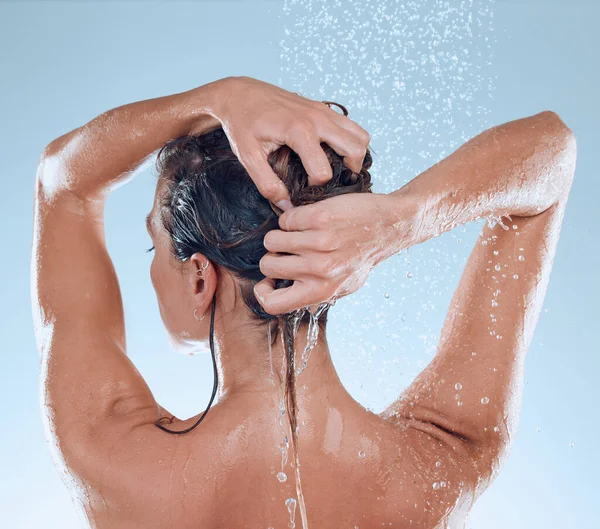 Gute Hygiene führt zu einem tollen Lebensstil. Studioaufnahme einer jungen Frau beim Duschen vor blauem Hintergrund. — Stockfoto