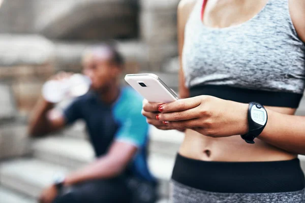 항상 루프에 있어. 신원을 알 수없는 여성 이 남자 친구와 함께 야외에서 운동을 하다가 핸드폰을 사용하고 있는 모습이 찍힌 사진.. — 스톡 사진