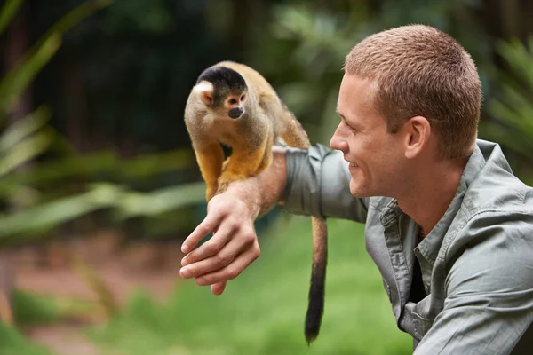 Hallo, kleine jongen. Schot van een jonge man die met een aapje omgaat in een wildpark.. — Stockfoto