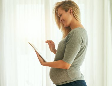 Böylece her hafta bebek gelişimimi kontrol edebilirim. Hamile bir kadının dijital tabletini kullanırken çekilmiş bir fotoğrafı..