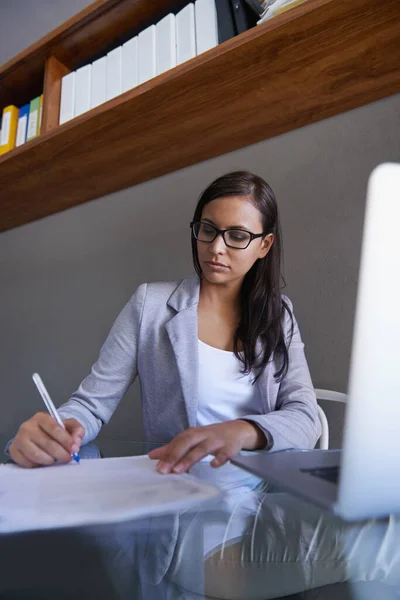 Finaliser un contrat d'affaires. Prise de vue d'une jeune femme d'affaires séduisante travaillant sur de la paperasse à son bureau. — Photo