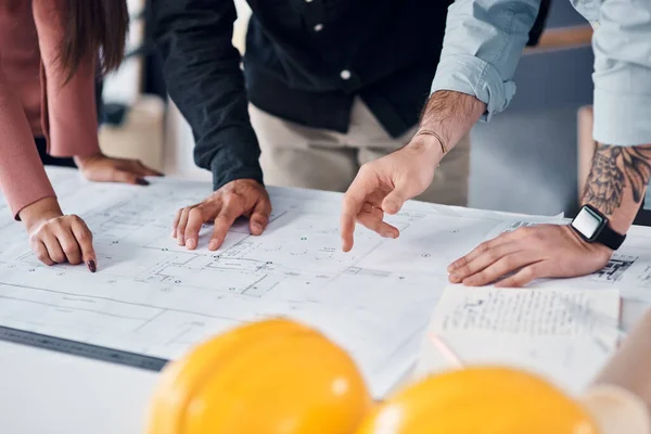 We hebben het vandaag allemaal op tafel gelegd. Opname van drie onherkenbare architecten die samen blauwdrukken en bouwplannen doornemen in hun kantoor.. — Stockfoto