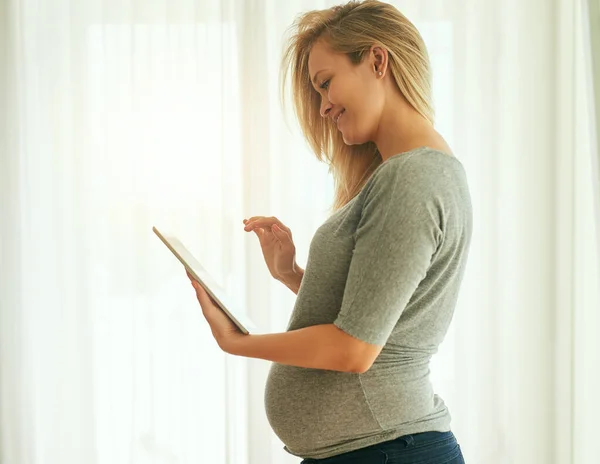 Takhle můžu kontrolovat vývoj svých dětí týden po týdnu. Vystřižený záběr těhotné ženy pomocí svého digitálního tabletu doma. — Stock fotografie