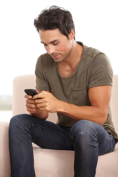 Rispondo a un messaggio. Un bel giovanotto seduto sul divano a scrivere un sms. — Foto Stock