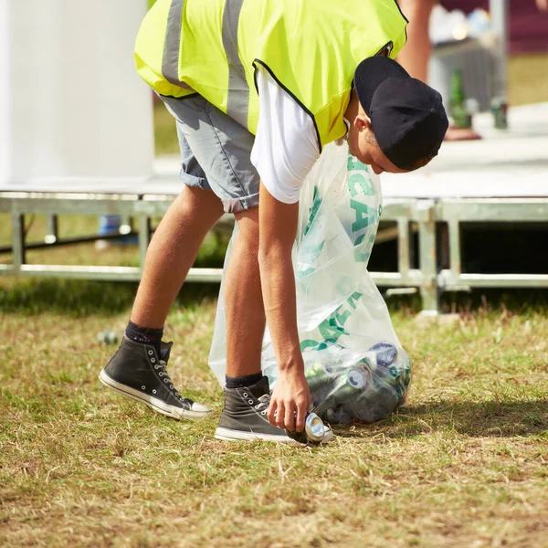 Halten Sie ihn sauber. Aufnahme eines jungen Mannes, der bei einem Outdoor-Festival Müll aufsammelt. — Stockfoto