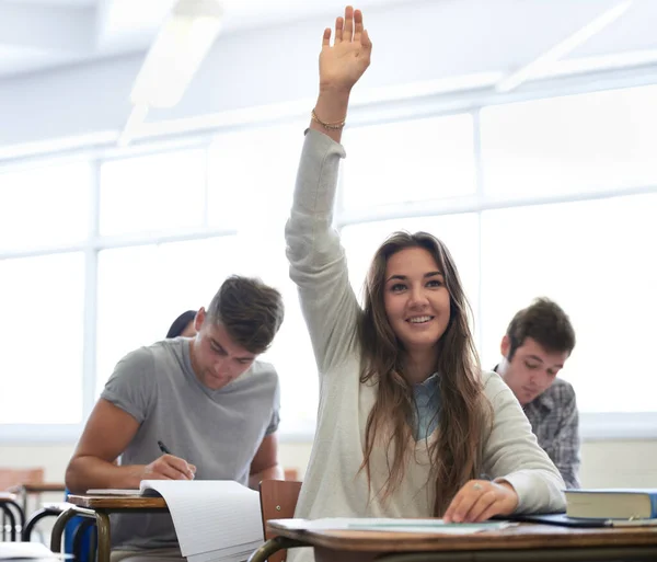 Siempre el primero en responder. Fotografía de una estudiante universitaria en clase con el brazo levantado para responder a una pregunta. — Foto de Stock