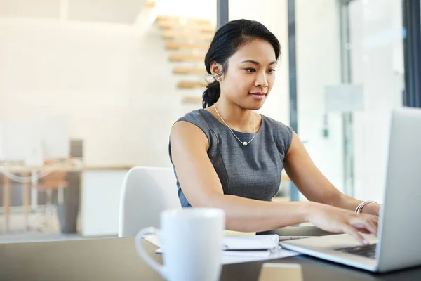 Haar werk is altijd van een uitzonderlijke kwaliteit. Gesneden foto van een jonge zakenvrouw die werkt op een laptop in een modern kantoor. — Stockfoto