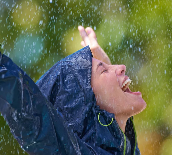 Se sentir réanimé sous la pluie. Coup de feu recadré d'une jeune femme debout joyeusement sous la pluie dans son imperméable. — Photo