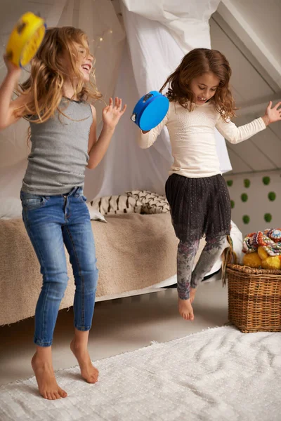 Schwestern schließen die besten Freunde. Aufnahme von zwei süßen kleinen Mädchen, die zu Hause mit Tamburinen spielen. — Stockfoto