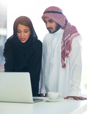 Sonuç üretme zamanı. Modern bir ofiste dizüstü bilgisayar kullanan iki müslüman iş arkadaşının fotoğrafı..