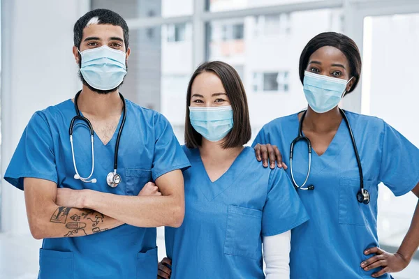 Це наша мета забезпечити вам оптимальне здоров'я. Портрет групи лікарів, які носять маски для обличчя в лікарні . — стокове фото