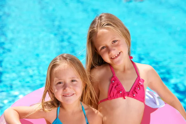 Rocas de verano. Dos niñas usando un tubo inflable mientras nadan. — Foto de Stock