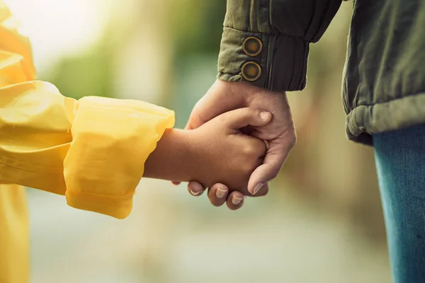 Siempre tomate de la mano al cruzar la calle. Primer plano de un niño irreconocible y su madre tomados de la mano bajo la lluvia afuera. —  Fotos de Stock