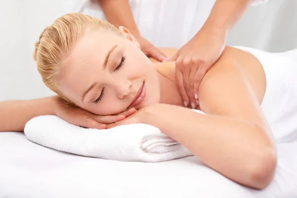 Diese Masseurin hat wunderbare Hände.... Eine schöne junge Frau genießt eine Massage in einem Wellnessbereich. — Stockfoto