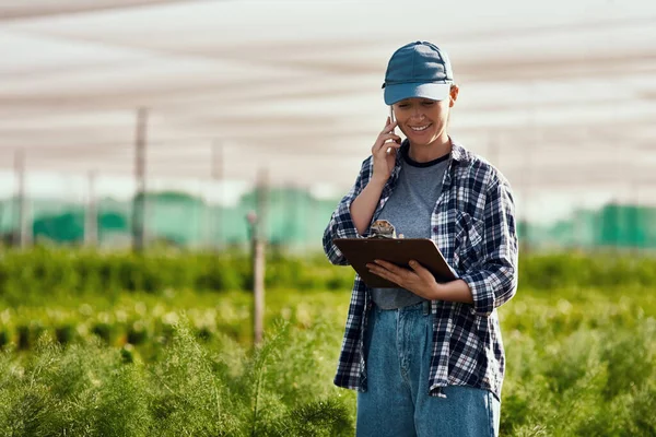 Im calling to give you the numbers.... Cropped shot of an attractive young female farmer making a phonecall while working on her farm. — Stock Photo, Image