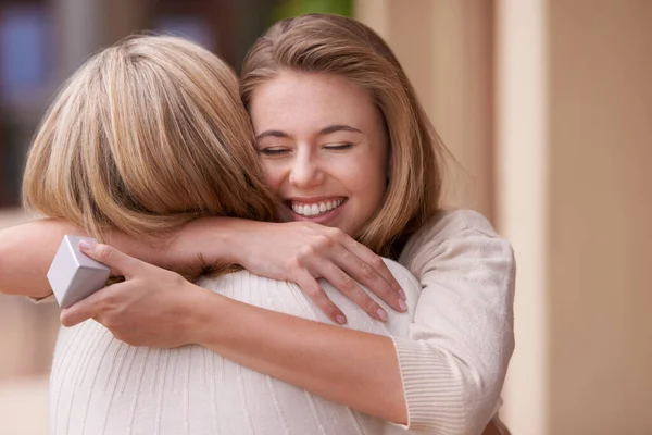 Te quiero, mamá. Una hija abrazando a su madre después de recibir un regalo. —  Fotos de Stock