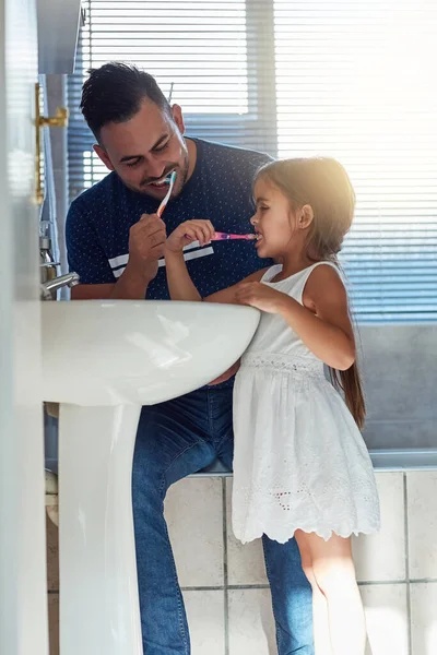 Es su hábito diario. Recorte de un padre y una hija cepillándose los dientes juntos en el lavabo del baño. — Foto de Stock