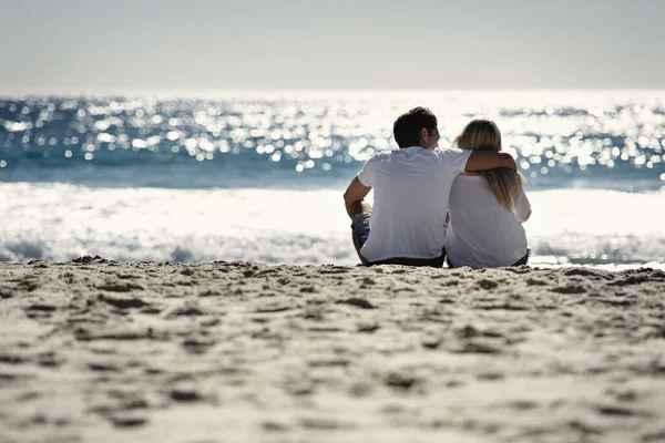 Esperando el atardecer. Una pareja sentada en una playa-Vista trasera. — Foto de Stock