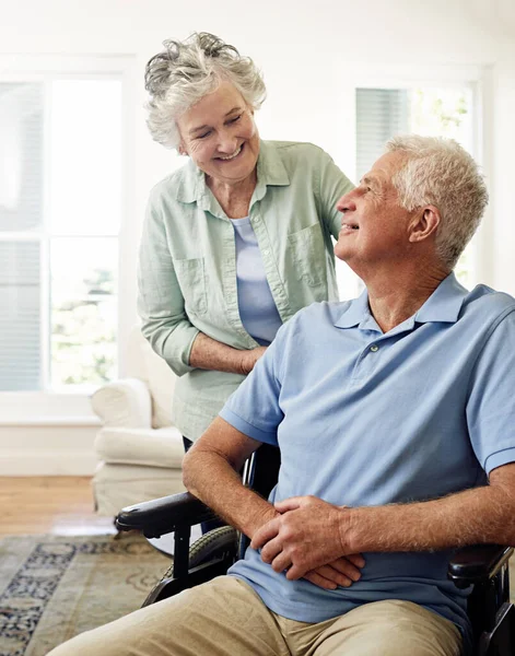 Cuidarse el uno al otro en sus años de invierno. Fotografía de un anciano sonriente en silla de ruedas y su esposa en casa. — Foto de Stock