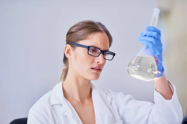 Avanzando la ciencia a través de la investigación metódica. Toma de un científico examinando un vaso de líquido mientras está de pie en un laboratorio. — Foto de Stock