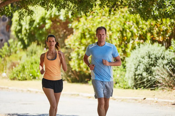 何もうまくいかない時は走りなさい。近所で二人でジョギングする幸せなカップルのショット. — ストック写真