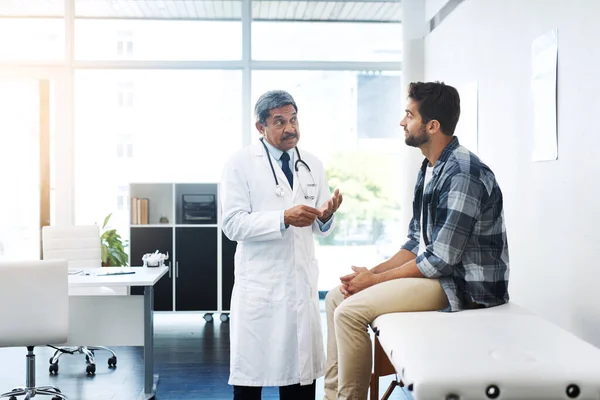 Ce qui semble être le problème monsieur. Prise de vue d'un homme mature médecin et patient ayant une discussion dans le bureau des médecins avant un bilan de santé. — Photo