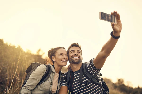 Algumas datas valem apenas a energia da bateria. Tiro de um casal feliz tirando uma selfie enquanto estava em uma viagem de caminhada. — Fotografia de Stock
