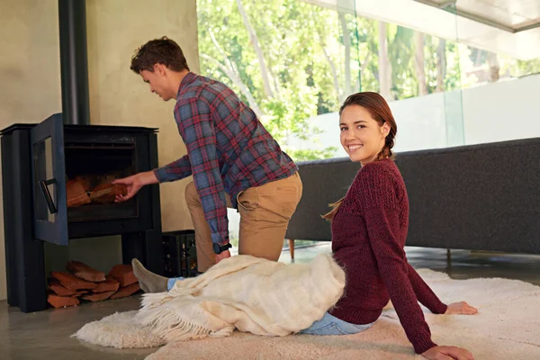 Theres nothing like staying home for real comfort. Shot of a young couple preparing their fireplace at home. — Stock Photo, Image