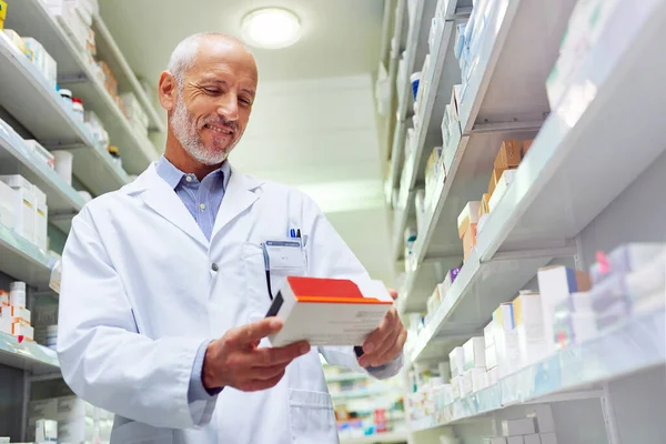 Ele é meticuloso quando se trata de gestão medicinal. Tiro de um farmacêutico maduro fazendo inventário em uma farmácia. — Fotografia de Stock