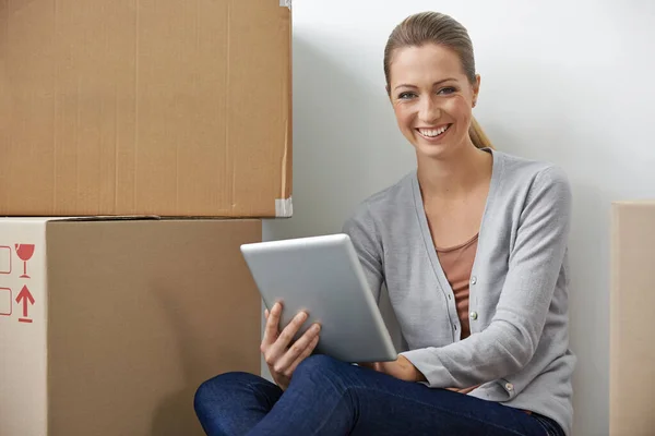 On bougeait, mais le travail ne s'arrête pas. Une jeune femme travaillant sur sa tablette numérique assise à côté de boîtes. — Photo