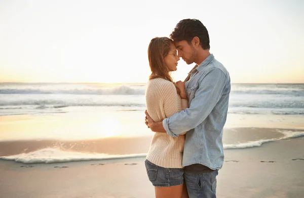 Saboreando este momento. Una feliz pareja joven celebrando su amor al atardecer en el be. — Foto de Stock