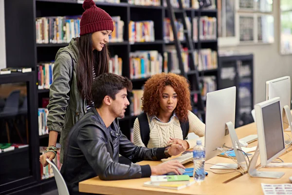 Diese Arbeitsgruppe weiß, was sie tut. Aufnahme einer Gruppe von Studenten, die gemeinsam an einem Computer in einer Universitätsbibliothek arbeiten. — Stockfoto