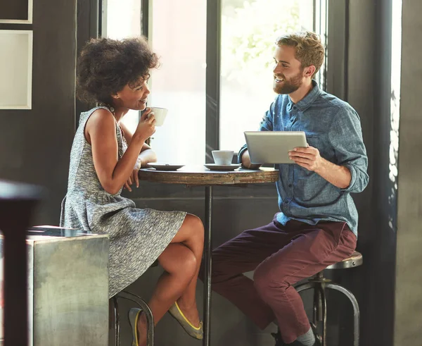 No primeiro encontro. Tiro de um jovem casal usando um tablet digital juntos em uma data de café. — Fotografia de Stock