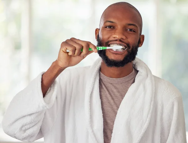 Recuerda cepillarte dos veces al día. Un disparo de un joven cepillándose los dientes en casa. — Foto de Stock