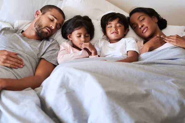 Our family is a dream come true. Shot of a beautiful young family of four fast asleep in bed together in their bedroom at home. — Stock Photo, Image